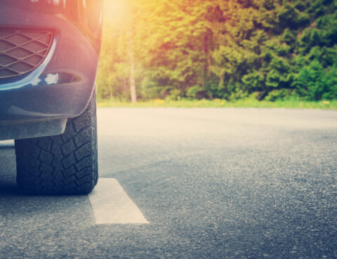 Osobné auto s letnými pneumatikami v horúčavách jazdiace po rozpálenom asfalte.